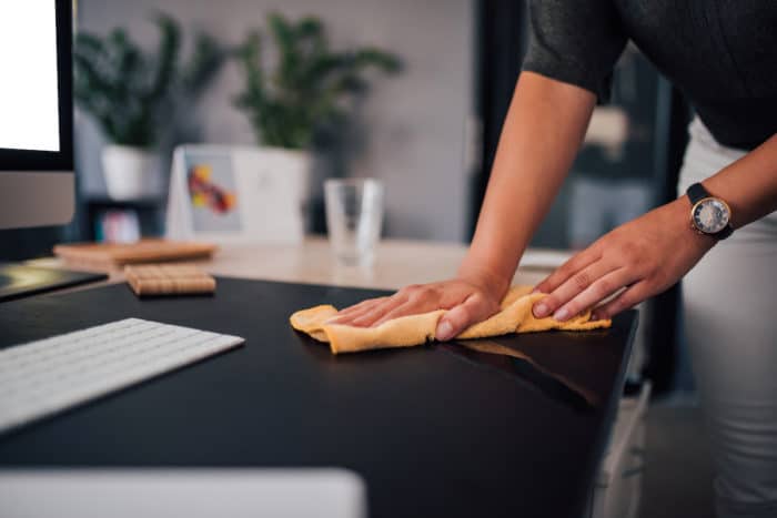 Businesswoman wiping sher work desk, close-up.